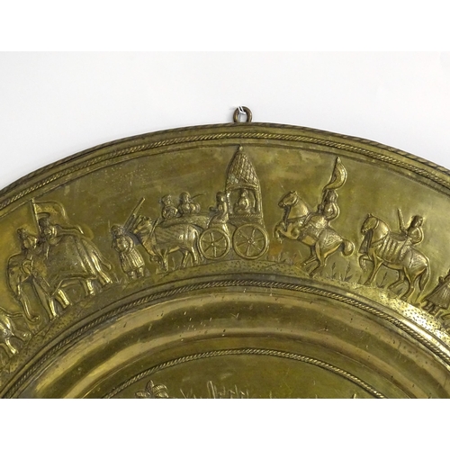 1273 - A large 20thC Indian brass charger with embossed decoration depicting an Indian procession with Impe... 