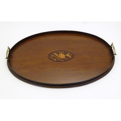 1284 - A late 19th / early 20thC mahogany tray of oval form with twin handles and central floral and foliat... 