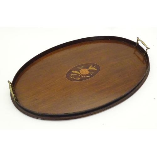 1284 - A late 19th / early 20thC mahogany tray of oval form with twin handles and central floral and foliat... 