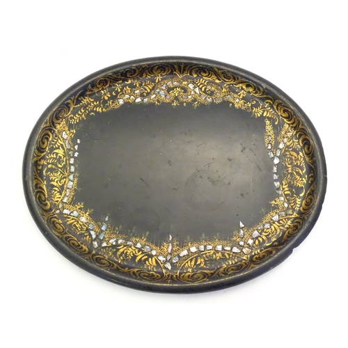 1286 - A 19thC papier mache lacquered tray of oval form with gilt foliate decoration and inlaid abalone det... 