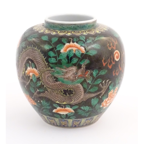 37 - A Chinese famille noir vase decorated with two dragons and a flaming pearl amongst flowers and folia... 