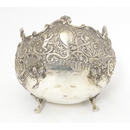 444 - A Continental white metal twin handled bowl with embossed floral, C scroll and cherub decoration, st... 