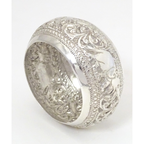 453 - A white metal napkin ring with elephant and acanthus decoration. Probably Indian.