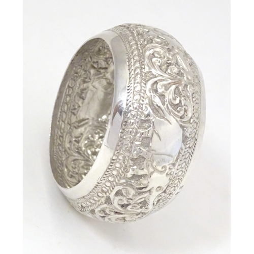 453 - A white metal napkin ring with elephant and acanthus decoration. Probably Indian.