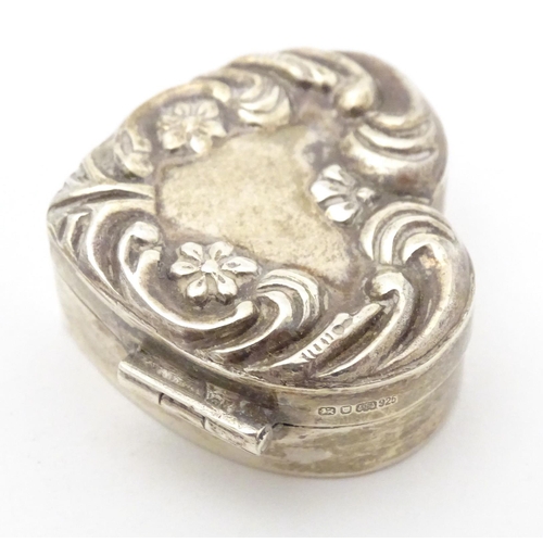 355 - A silver pill box of heart form with embossed decoration and hinged lid. Hallmarked London 1988 make... 