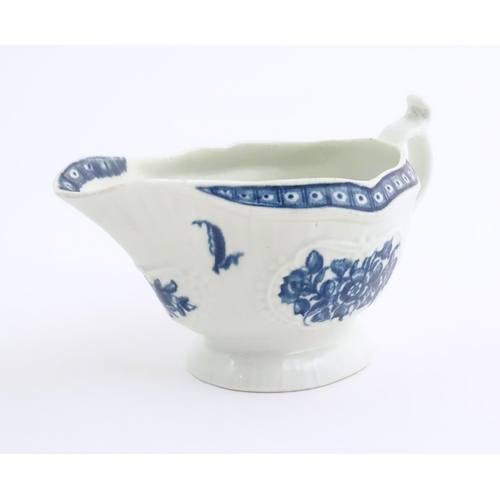 67 - An 18thC blue and white Worcester sauce boat with double scroll handle and thumb rest, decorated in ... 