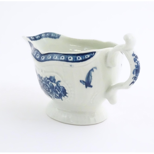 67 - An 18thC blue and white Worcester sauce boat with double scroll handle and thumb rest, decorated in ... 