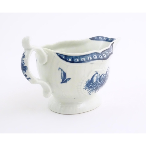 67 - An 18thC blue and white Worcester sauce boat with double scroll handle and thumb rest, decorated in ... 