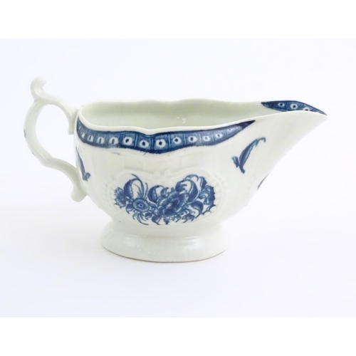 67 - An 18thC blue and white Worcester sauce boat with double scroll handle and thumb rest, decorated in ... 