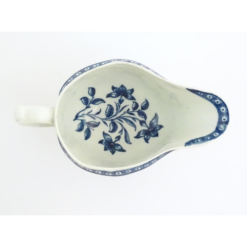 67 - An 18thC blue and white Worcester sauce boat with double scroll handle and thumb rest, decorated in ... 