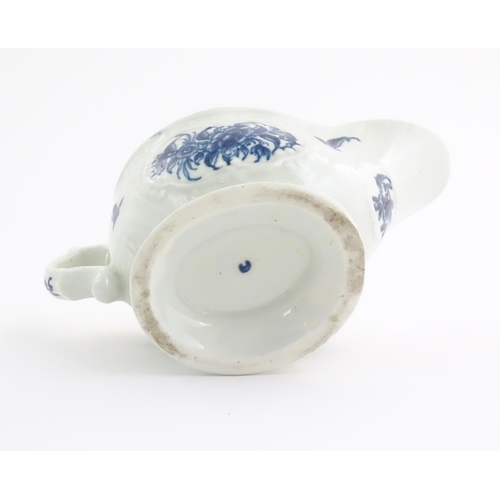 67 - An 18thC blue and white Worcester sauce boat with double scroll handle and thumb rest, decorated in ... 