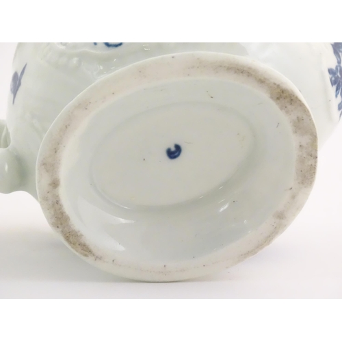 67 - An 18thC blue and white Worcester sauce boat with double scroll handle and thumb rest, decorated in ... 