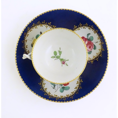 74 - A Continental cup and saucer the blue ground decorated with hand painted panels depicting floral ros... 