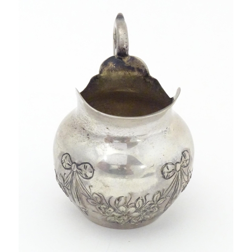 322 - A small Continental .800 silver cream jug with ribbon and swag decoration. Marked under possibly Han... 