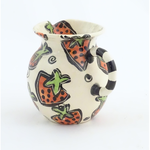 166 - A studio pottery jug and bowl decorated with hand painted strawberry detail by Liz Riley. Marked und... 