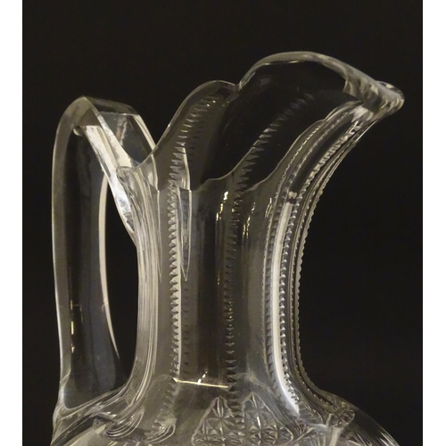 224 - A cut glass claret jug with a pair of cut glass pedestal drinking glasses. The jug 10 1.2