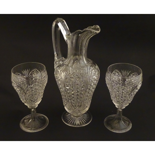 224 - A cut glass claret jug with a pair of cut glass pedestal drinking glasses. The jug 10 1.2