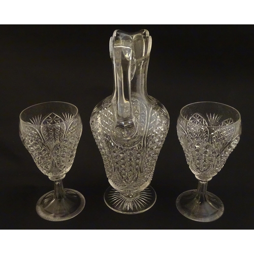 224 - A cut glass claret jug with a pair of cut glass pedestal drinking glasses. The jug 10 1.2