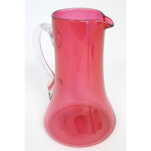 245 - A cranberry glass jug with clear glass loop handle. 10