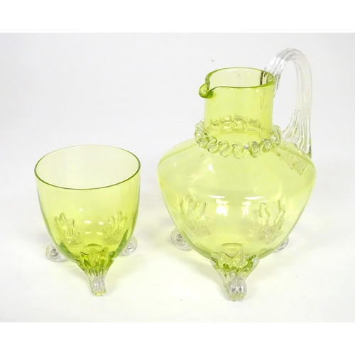 268 - A yellow glass water jug with clear glass handle and feet, together with a matching glass. The jug  ... 