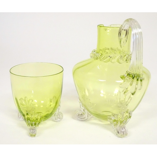 268 - A yellow glass water jug with clear glass handle and feet, together with a matching glass. The jug  ... 