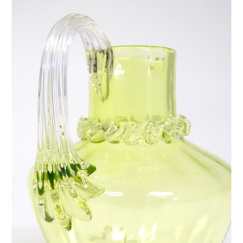 268 - A yellow glass water jug with clear glass handle and feet, together with a matching glass. The jug  ... 