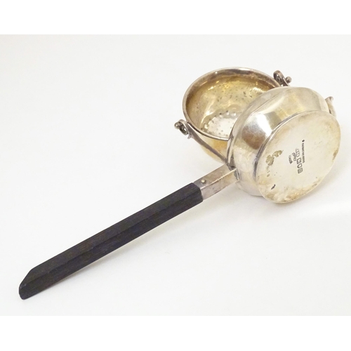 396 - A silver tea strainer modelled as a stylised teapot with suspended strainer above, the base with pou... 