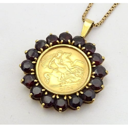 720 - A 1914 half sovereign coin within a 9ct gold pendant mount bordered by garnets, on a 9ct gold chain.... 