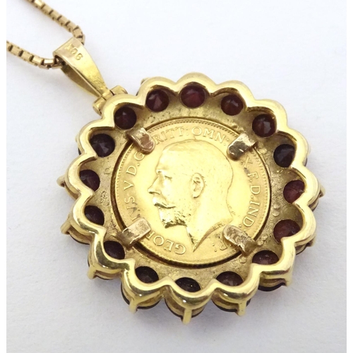 720 - A 1914 half sovereign coin within a 9ct gold pendant mount bordered by garnets, on a 9ct gold chain.... 