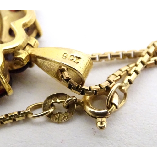 720 - A 1914 half sovereign coin within a 9ct gold pendant mount bordered by garnets, on a 9ct gold chain.... 