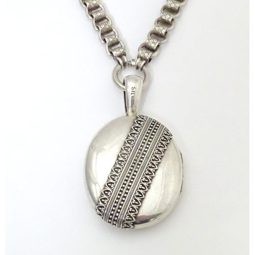 736 - A silver and white metal locket on chain, the locket with banded decoration. Locket approx. 2 1/2