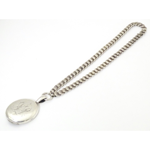 736 - A silver and white metal locket on chain, the locket with banded decoration. Locket approx. 2 1/2