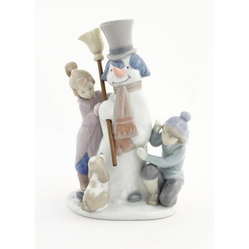 118 - A Lladro figure modelled as figures with a dog building a snowman, The Snowman, model no. 5713. Mark... 