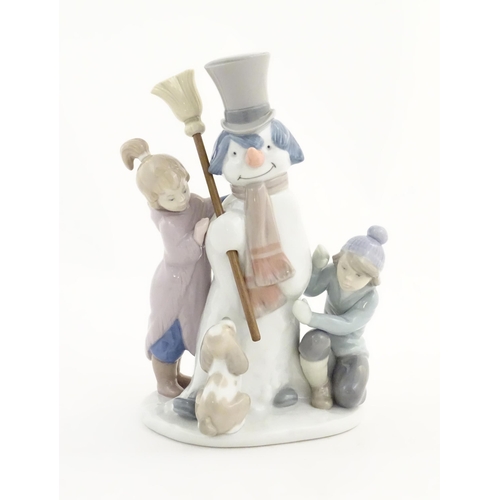 118 - A Lladro figure modelled as figures with a dog building a snowman, The Snowman, model no. 5713. Mark... 