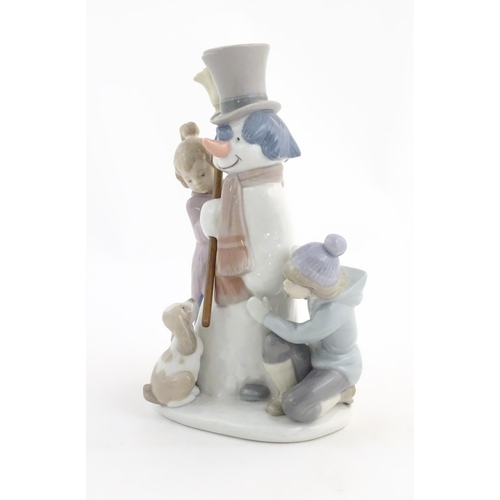 118 - A Lladro figure modelled as figures with a dog building a snowman, The Snowman, model no. 5713. Mark... 