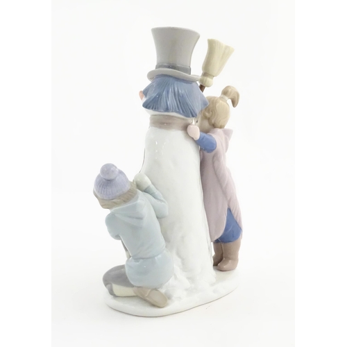 118 - A Lladro figure modelled as figures with a dog building a snowman, The Snowman, model no. 5713. Mark... 