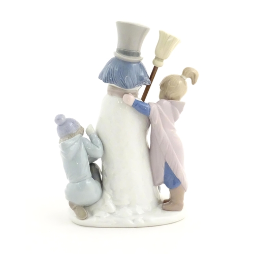 118 - A Lladro figure modelled as figures with a dog building a snowman, The Snowman, model no. 5713. Mark... 