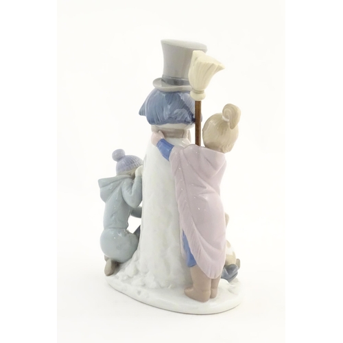 118 - A Lladro figure modelled as figures with a dog building a snowman, The Snowman, model no. 5713. Mark... 