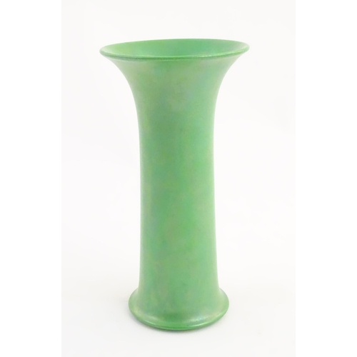 86 - A Ruskin pottery green lustre vase of cylindrical form with a flared rim. Impressed marks under 1918... 