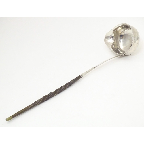 387 - A later 18th / early 19thC white metal toddy / punch ladle with a whale bone handle. Approx. 11 1/2