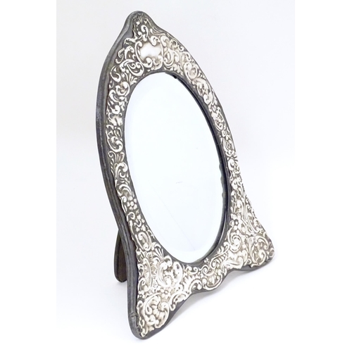 416 - An easel back mirror with white metal surround with embossed decoration. Approx. 12 1/2