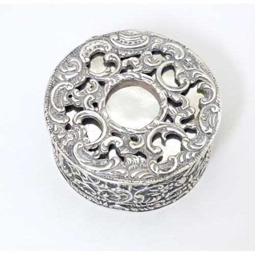 528 - A Victorian silver and white metal box of circular form with hinge lid and scrolling foliate decorat... 