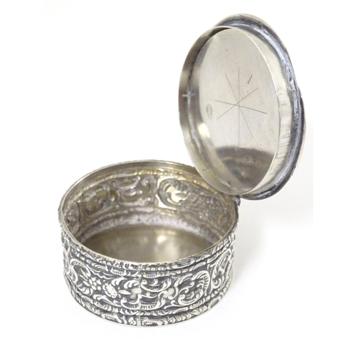 528 - A Victorian silver and white metal box of circular form with hinge lid and scrolling foliate decorat... 