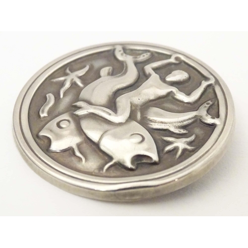 617 - Georg Jensen : A silver brooch of circular form  with embossed decoration depicting a merman on a wh... 