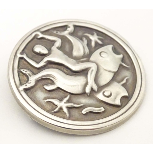 617 - Georg Jensen : A silver brooch of circular form  with embossed decoration depicting a merman on a wh... 