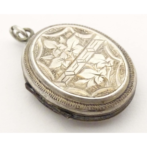 638 - A white metal pendant locket of oval form with foliate decoration 1 1/4