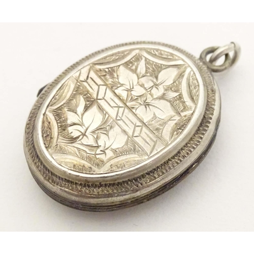 638 - A white metal pendant locket of oval form with foliate decoration 1 1/4