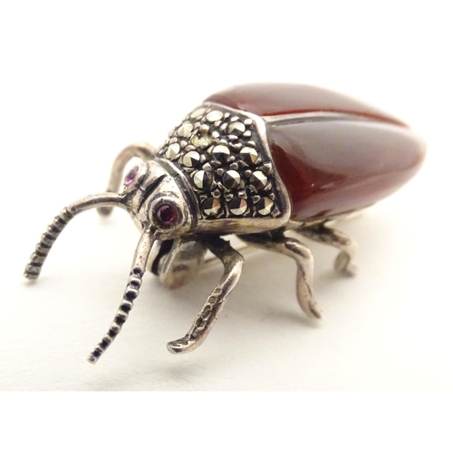 652 - A silver and white metal brooch formed as a beetle, with red stone eyes, marcasite detail and garnet... 