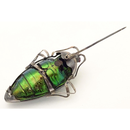 655 - A beetle brooch with white metal mounts, red stone eyes and filigree detail. 2 1/4