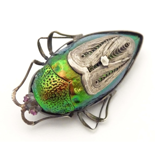 655 - A beetle brooch with white metal mounts, red stone eyes and filigree detail. 2 1/4